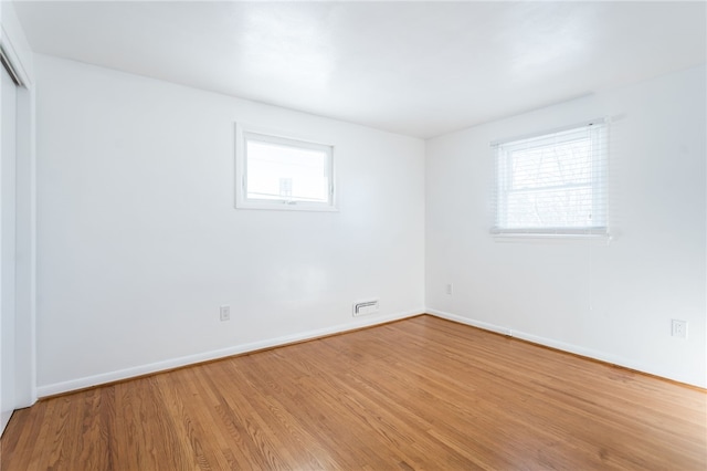 empty room with visible vents, baseboards, and wood finished floors