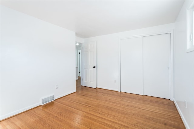 unfurnished bedroom with visible vents, light wood-style flooring, and baseboards