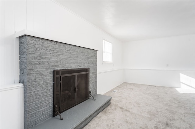 interior space with carpet flooring, a fireplace with raised hearth, and visible vents