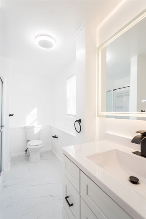 full bathroom featuring toilet, marble finish floor, a stall shower, and vanity