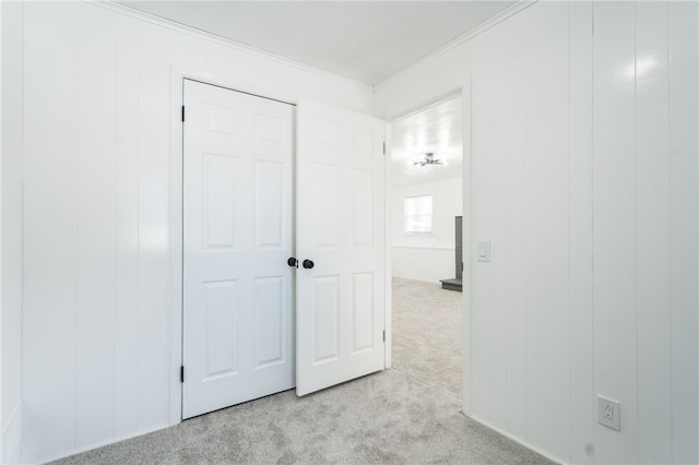 unfurnished bedroom with a closet, light colored carpet, and crown molding