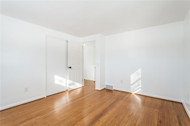 spare room featuring visible vents, light wood-style flooring, and baseboards