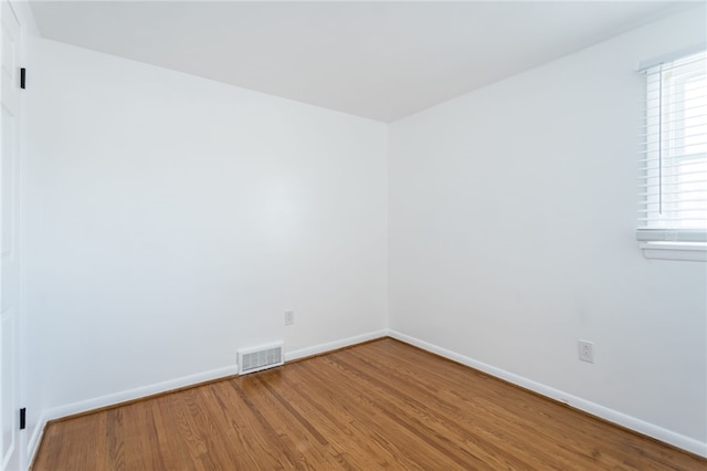 empty room featuring visible vents, baseboards, and wood finished floors