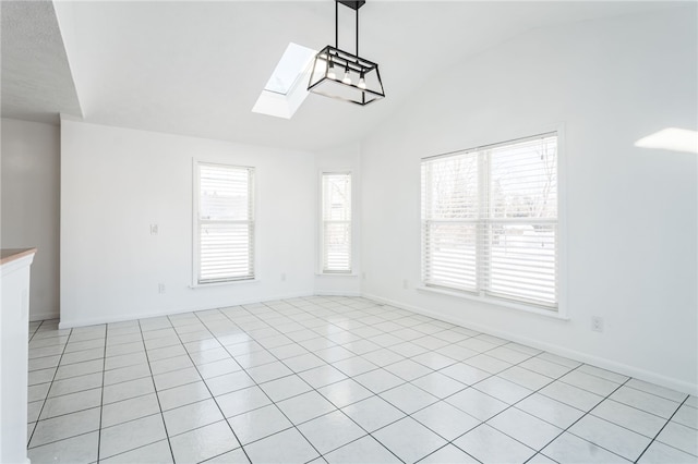 spare room featuring lofted ceiling with skylight and baseboards