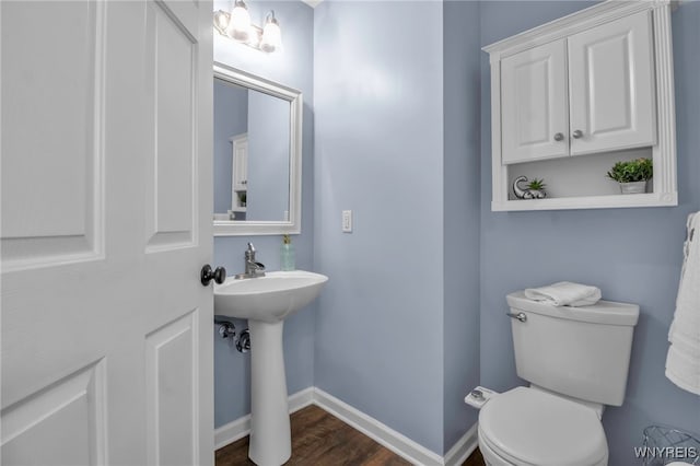 bathroom featuring toilet, wood finished floors, baseboards, and a sink