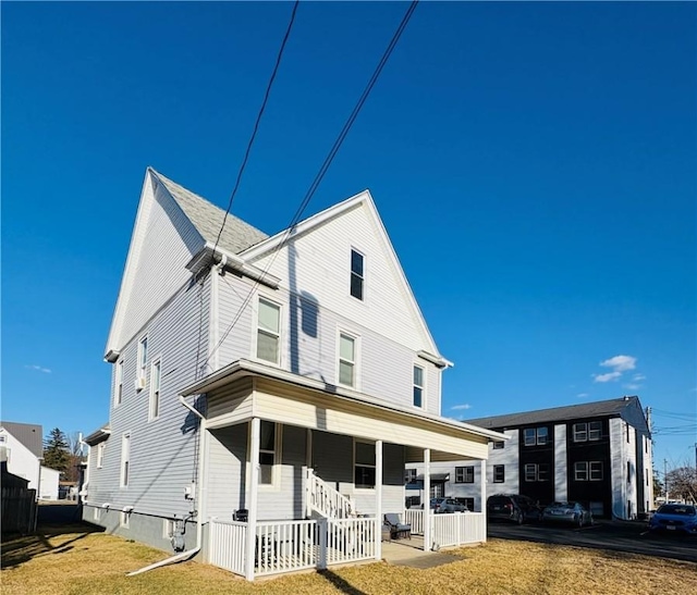 back of property featuring a yard and covered porch