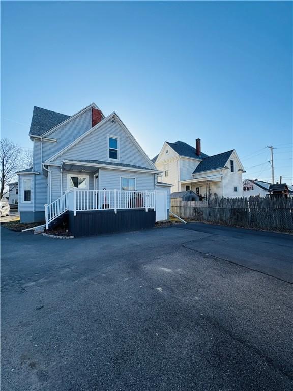 bungalow-style home with fence and a chimney