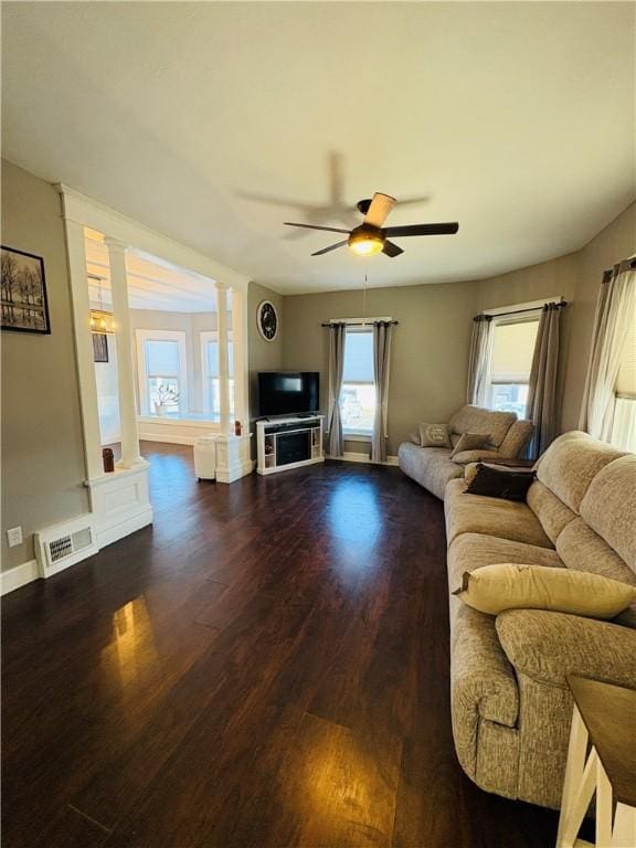 living room featuring visible vents, ceiling fan, baseboards, wood finished floors, and ornate columns