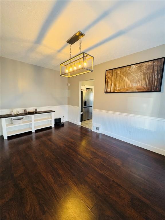 unfurnished room with a wainscoted wall, visible vents, and wood finished floors