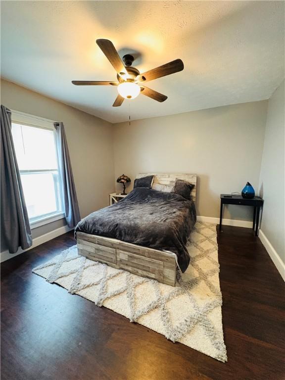 bedroom with ceiling fan, baseboards, and wood finished floors