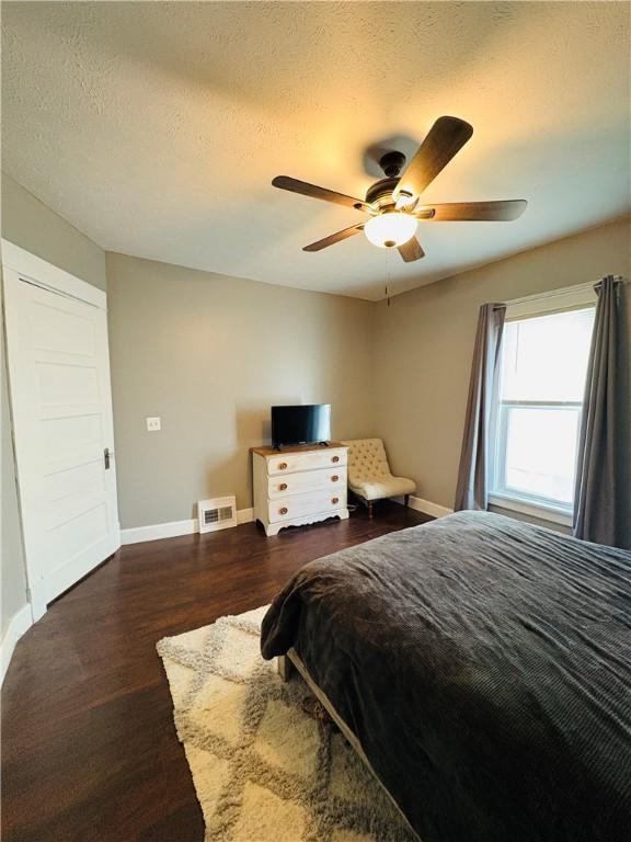 bedroom featuring visible vents, baseboards, a textured ceiling, and wood finished floors