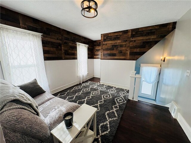 living area featuring visible vents, baseboards, a textured ceiling, and wood finished floors