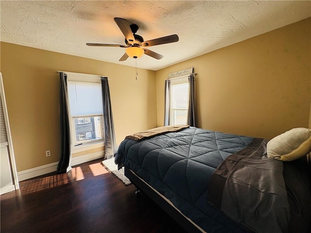 bedroom featuring dark wood finished floors, ceiling fan, a textured ceiling, and baseboards