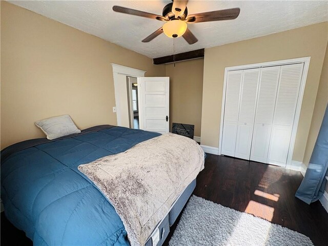 bedroom with dark wood-type flooring, ceiling fan, baseboards, a closet, and a textured ceiling