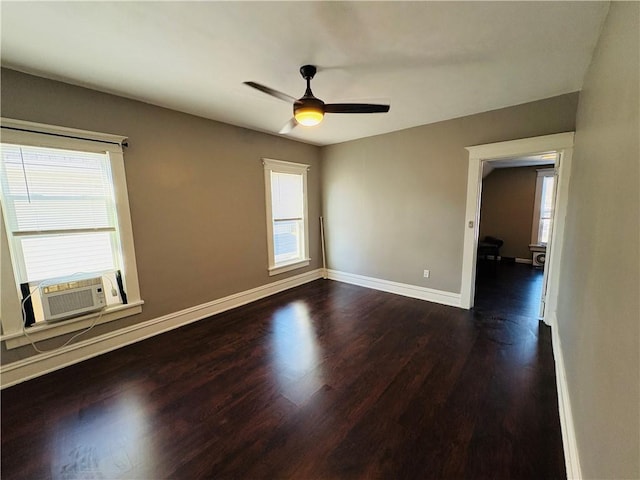 spare room featuring dark wood finished floors, cooling unit, baseboards, and a wealth of natural light