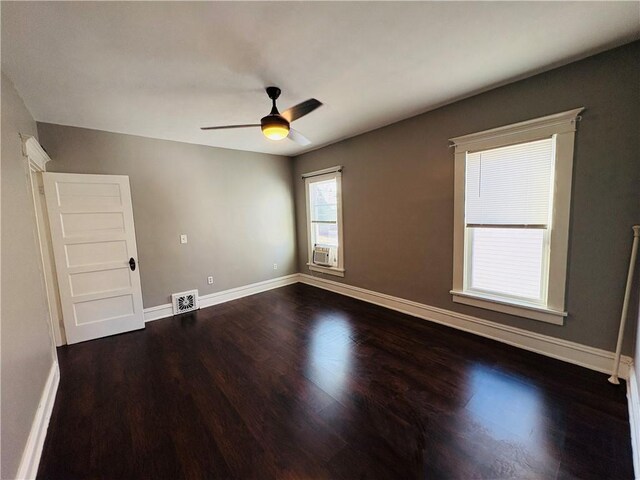 unfurnished room featuring visible vents, a ceiling fan, cooling unit, baseboards, and dark wood-style flooring