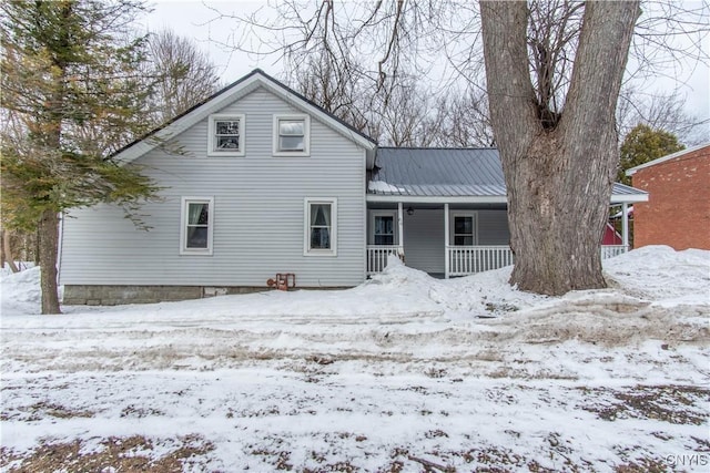 view of front facade with a porch, metal roof, and a garage