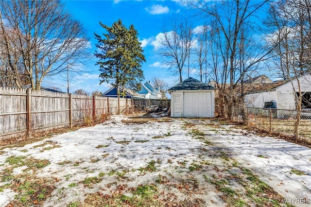 snowy yard featuring a storage unit, a fenced backyard, and an outdoor structure