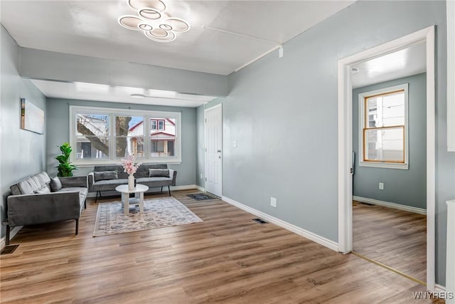 living area with visible vents, baseboards, and wood finished floors