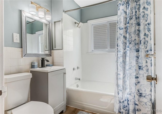 bathroom with toilet, vanity, tile walls, and shower / bath combo with shower curtain