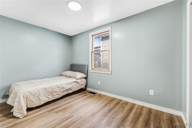 bedroom with visible vents, baseboards, and wood finished floors