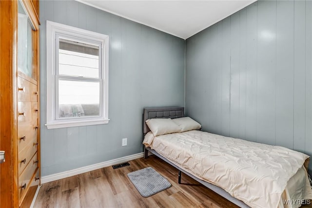 bedroom with visible vents, baseboards, and wood finished floors