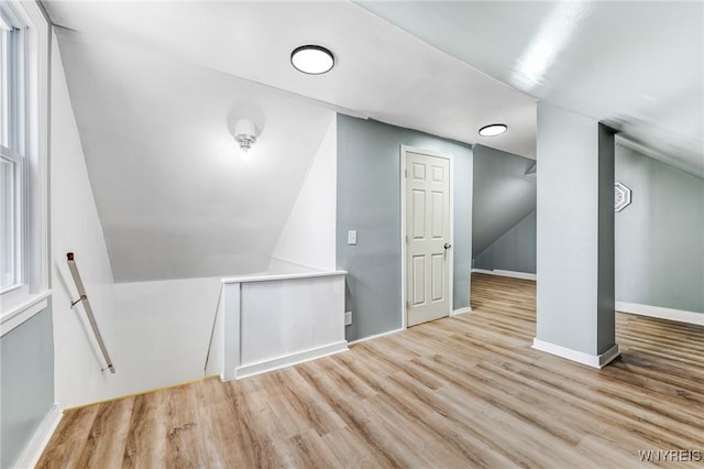 additional living space featuring baseboards, wood finished floors, and vaulted ceiling