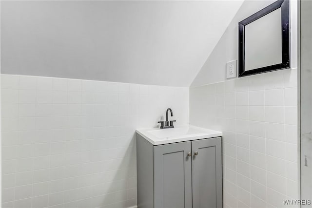 bathroom with lofted ceiling, tile walls, and vanity