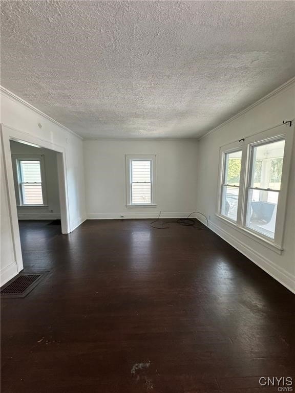 unfurnished room with visible vents, baseboards, dark wood-type flooring, a textured ceiling, and crown molding