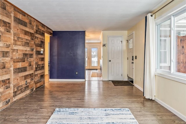 entrance foyer with wood walls, baseboards, and wood finished floors