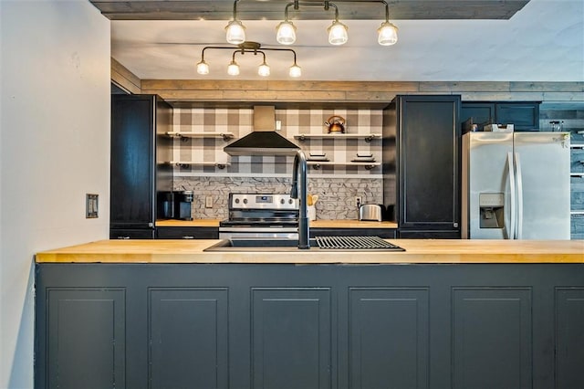 kitchen with wall chimney range hood, tasteful backsplash, appliances with stainless steel finishes, and wood counters