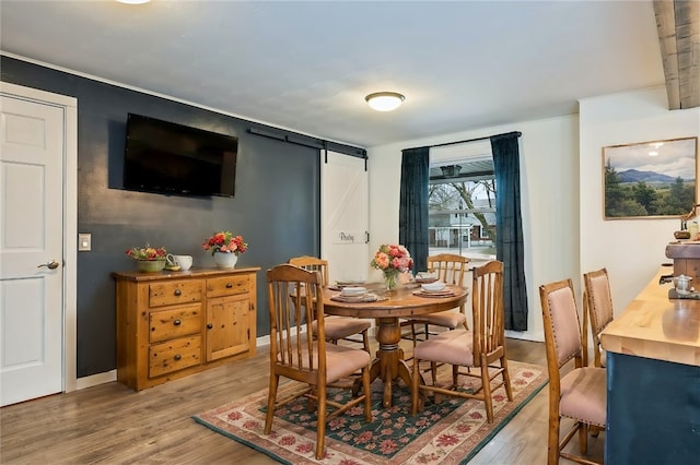 dining room with light wood-type flooring and a barn door