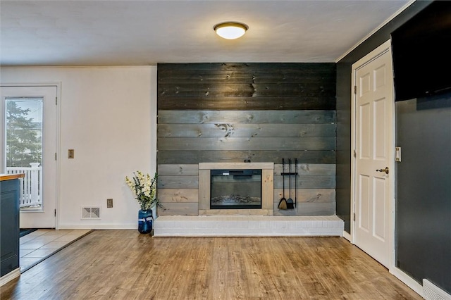 unfurnished living room with baseboards, wood finished floors, visible vents, and a large fireplace