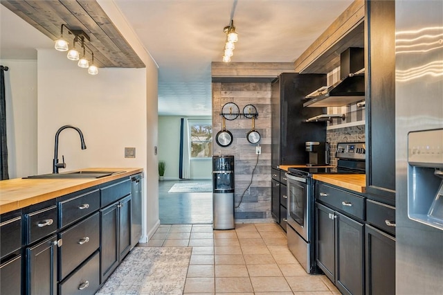 kitchen featuring a sink, wooden counters, light tile patterned floors, appliances with stainless steel finishes, and open shelves