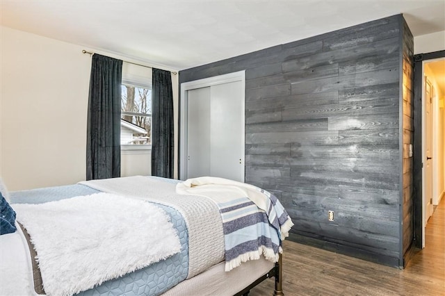 bedroom featuring a closet, wooden walls, and wood finished floors