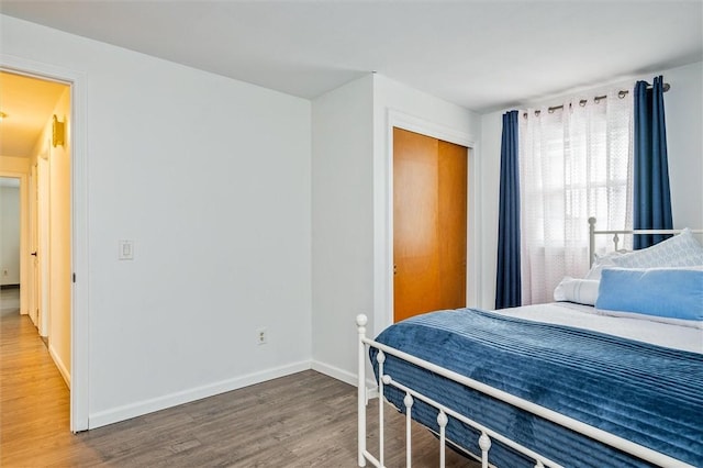 bedroom featuring wood finished floors, baseboards, and a closet