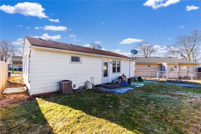 back of property with a fenced backyard, a lawn, and central AC