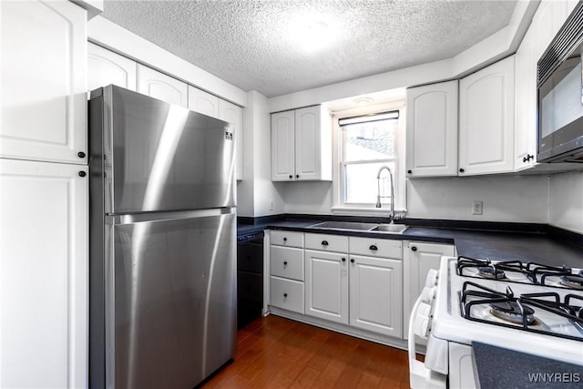 kitchen featuring dark wood-style floors, a sink, black appliances, white cabinets, and dark countertops