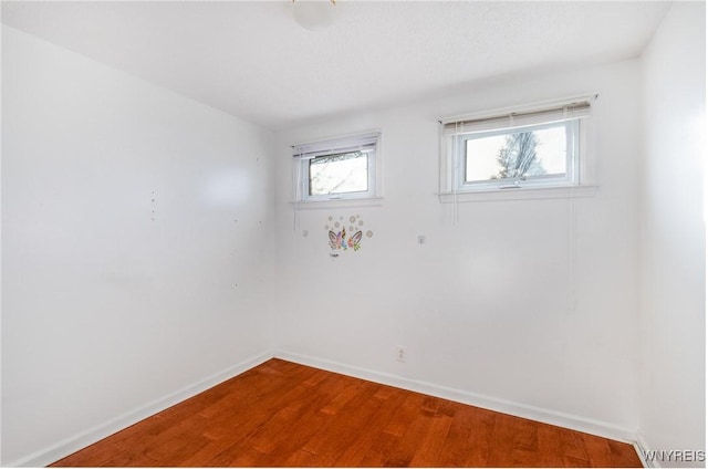 unfurnished room with wood finished floors, baseboards, and a wealth of natural light