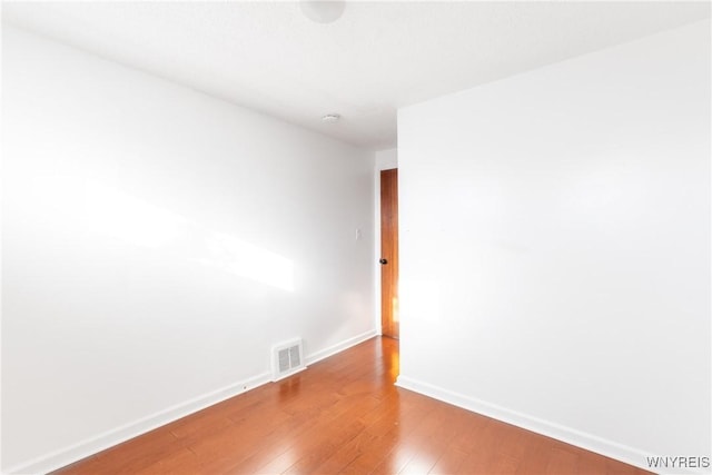 unfurnished room featuring visible vents, baseboards, and hardwood / wood-style floors