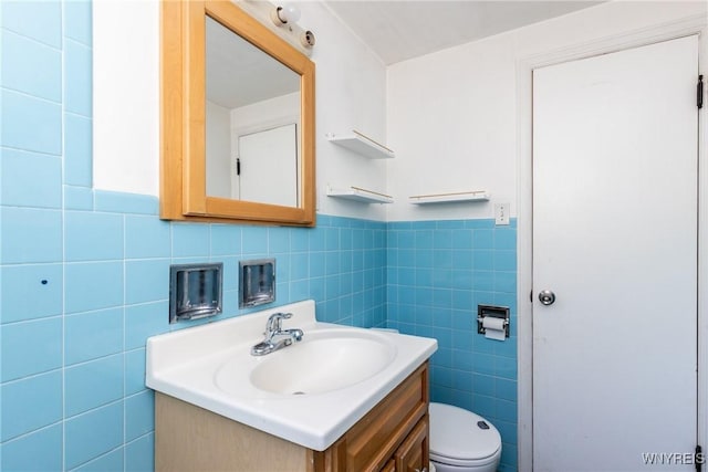 bathroom with vanity, tile walls, toilet, and wainscoting