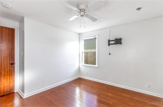 empty room featuring ceiling fan, wood finished floors, baseboards, and a textured ceiling