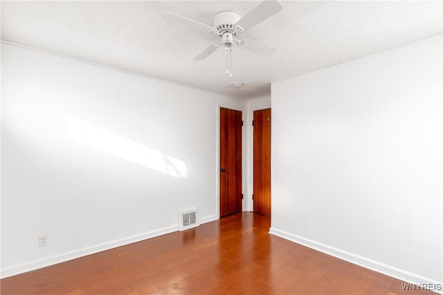 unfurnished room featuring visible vents, baseboards, wood finished floors, a textured ceiling, and a ceiling fan