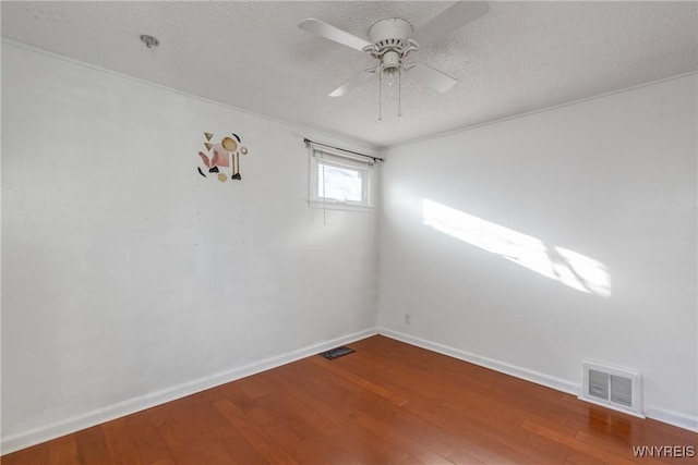 spare room featuring baseboards, wood finished floors, visible vents, and a textured ceiling