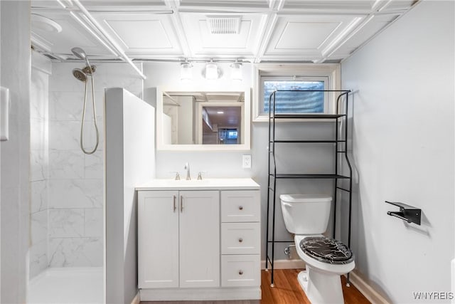 bathroom featuring visible vents, toilet, tiled shower, and wood finished floors