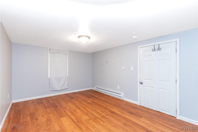 unfurnished room featuring baseboards, light wood finished floors, and a baseboard radiator