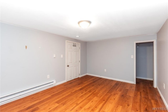 spare room featuring light wood-style flooring, baseboards, and a baseboard radiator