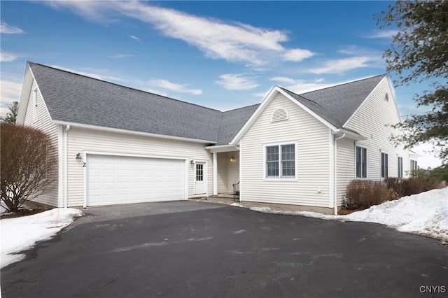 view of front of house featuring driveway, a garage, and roof with shingles