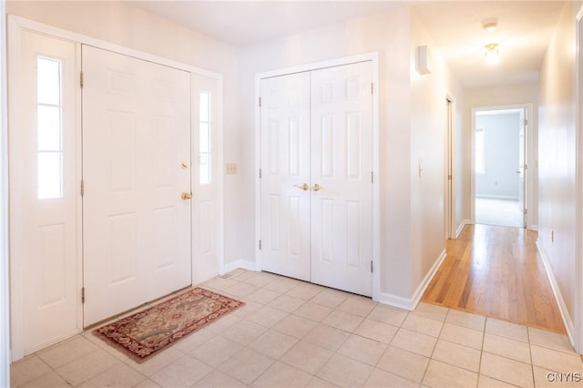 foyer with plenty of natural light, light tile patterned flooring, and baseboards