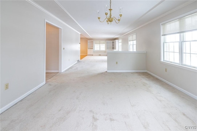 spare room with carpet flooring, baseboards, a chandelier, and crown molding